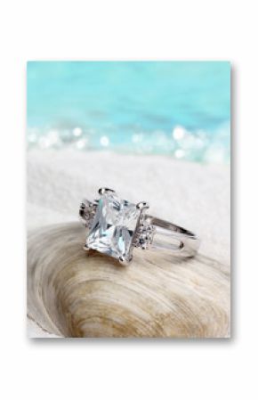 Jewelry ring with clean diamond on sand beach background, soft f