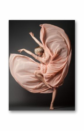 Woman in light chiffon dress dancing sensually on black plain background.