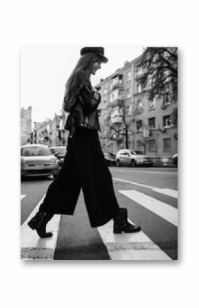 Beautiful girl with sunglasses. A model in a stylish wide-brimmed hat at a pedestrian crossing. Harmoniously similar clothes in gray tones. Street style shooting. Women's fashion.