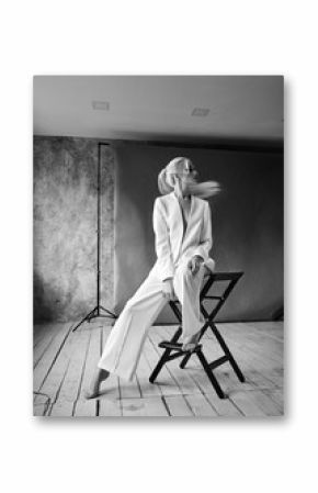 High Fashion blond woman in white suit. Elegant Style model. Dynamic shot in Photo studio shooting