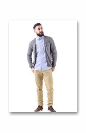 Well dressed man fashion model in gray cardigan looking up with hands in back pockets. Full body length portrait isolated on white studio background. 