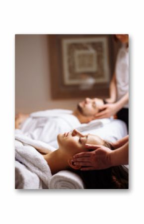 happy young beautiful couple enjoying head massage at the spa