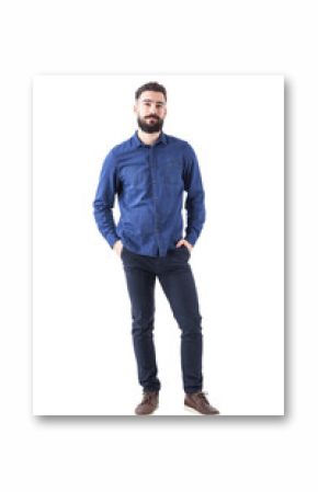 Relaxed young man wearing blue denim shirt with hands in pockets looking at camera. Full body isolated on white background. 