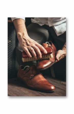 bootblack cleans brown monk shoes with a brush and shoe polish