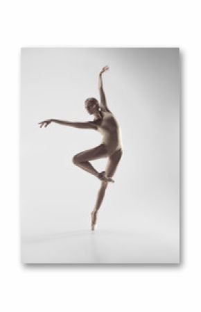 Young graceful female ballet dancer or classic ballerina dancing on white studio. Caucasian model on pointe shoes