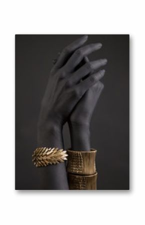 Black woman's hand with gold jewelry. Oriental Bracelets on a black painted hand.