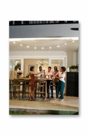 Friends celebrating with champagne outdoors, toasting under string lights at night