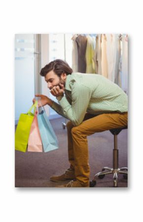 Pastel shopping bags resting on rolling stool in retail showroom, with frosted glass partition
