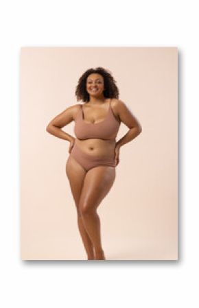 Young biracial plus size model poses on beige background, copy space