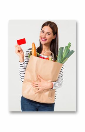 Portrait of beautiful smiling woman holding shopping paper bag with organic fresh food isolated on white background.