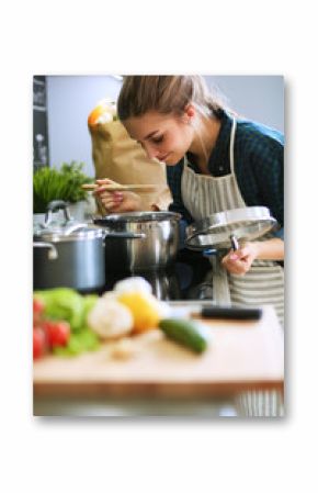 Young woman standing by the stove in the kitchen .