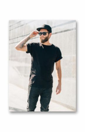 Hipster handsome male model with beard  wearing black blank  t-shirt with space for your logo or design in casual urban style