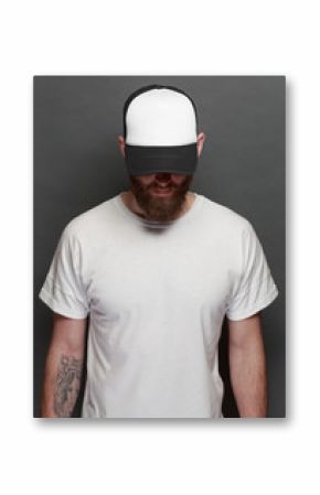 Hipster handsome male model with beard wearing white blank t-shirt and a baseball cap with space for your logo or design in casual urban style