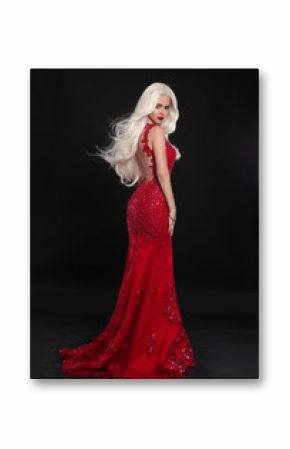 Beautiful blond woman in red dress isolated on black background. Elegant lady in long luxurious gown posing at camera.