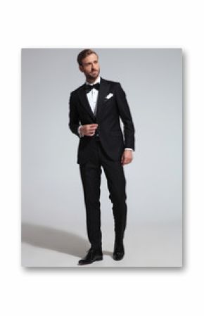 elegant man in tuxedo walks to side and looks away