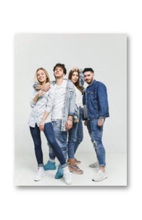 Group of smiling friends in fashionable jeans. The young men and woman posing at studio. The fashion, people, happy, lifestyle, clothes concept