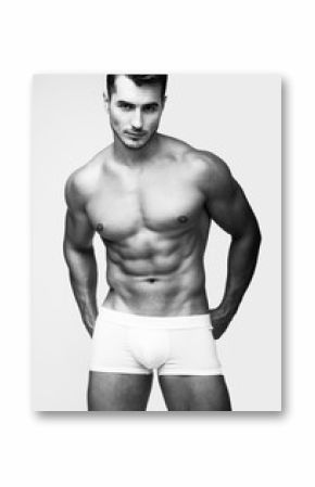 Portrait of handsome young man with stylish haircut in white underwear posing over gray background. Perfect hair & skin. Close up. Studio shot
