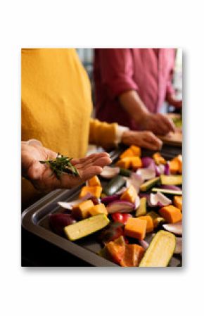 Midsection of senior caucasian couple preparing vegetables, seasoning with rosemary, copy space