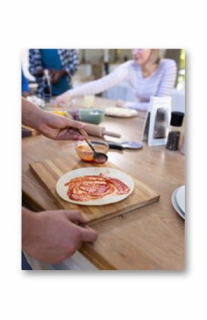 Happy diverse group of teenage friends cooking and making pizza in kitchen