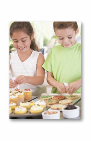 Two children decorating cookies smiling