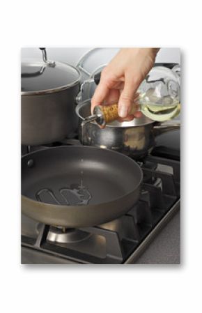 Cooking oil being pourred from a glass bottle into a frying-pan.