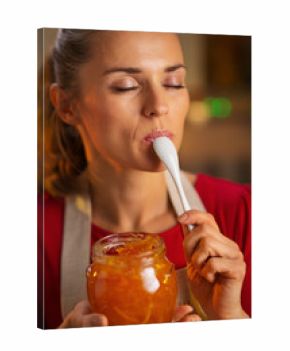 Young housewife tasting a spoon of homemade orange marmalade