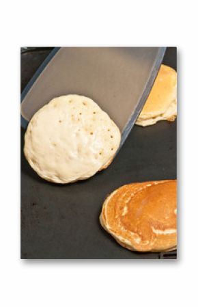 Flipping pancake on a hot grill with a metal spatula