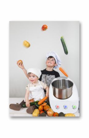 Niños cocinando verduras frescas con un robot de cocina reflejando conceptos familiares de diversión, facilidad, colaboración y educación