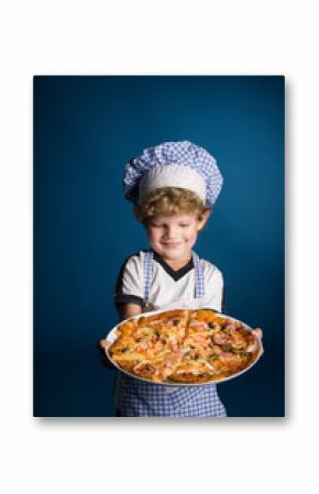 Little boy chef with a pizza on a blue background in studio