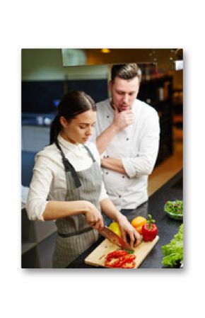 Trainee preparing slow food under chef control
