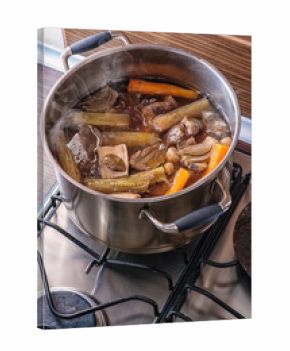 traditional beef broth with vegetable, bones and ingredients in pot, cooking recipe