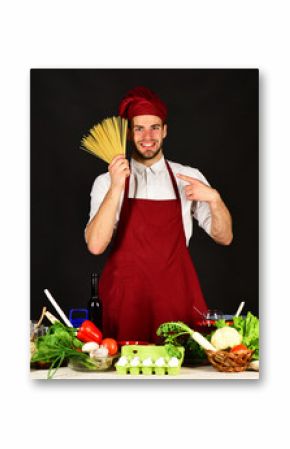 Cook works in kitchen near table with vegetables and tools.