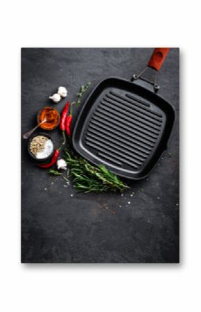 Empty cast-iron grill pan with ingredients for cooking on black background, top view