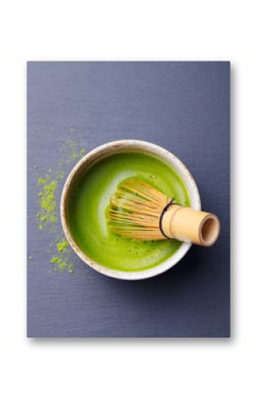 Matcha green tea cooking process in a bowl with bamboo whisk. Black slate background.
