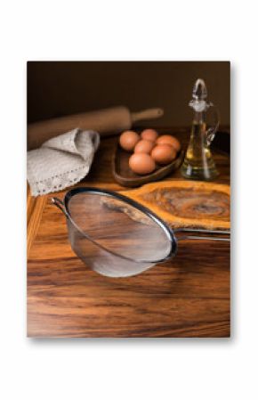 sieve, rolling pin, dough, egg, oil on wooden table
