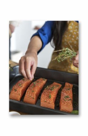 Woman adding spices and herb to raw salmon