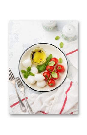 Cherry tomatoes, basil, mozzarella cheese and olive oil on white background. Italian food background. Top view.