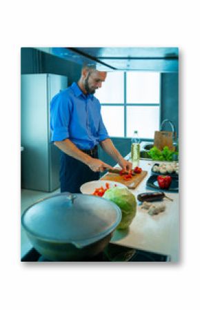 The man in the home kitchen. He cuts the pepper with a knife.