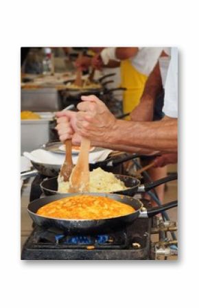 Cooking frico, the typical Friulian dish made of heated cheese and potatoes.