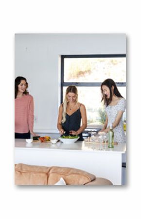 Preparing salad together, friends cooking and chatting in modern kitchen