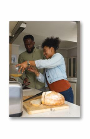 Couple preparing meal together in kitchen, smiling and enjoying cooking time