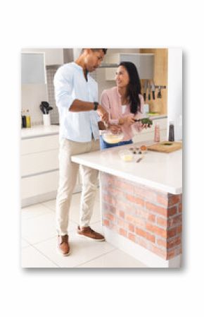 Couple cooking together in modern kitchen, preparing fresh vegetables and smiling