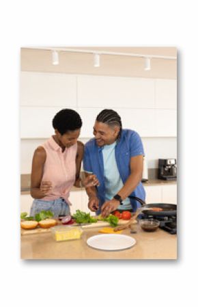 Diverse couple cooking dinner in modern home kitchen, preparing lettuce and burger buns