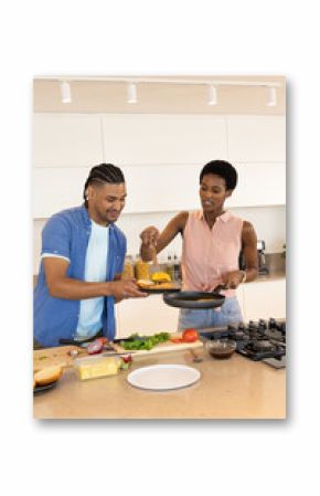 Cooking diverse couple preparing vegetables on island in modern kitchen with chef's knife