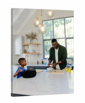 African American father and son preparing sandwich at marble island with board, backpack, notebook