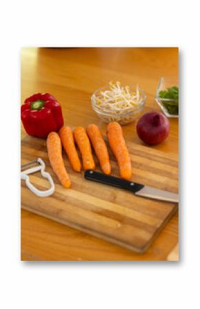 preparing fresh vegetables, chopping carrots, bell pepper, and onion on cutting board