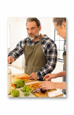 Preparing fresh vegetables, mature couple cooking together in bright kitchen, at home