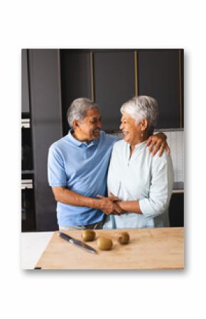 Elderly couple laughing in kitchen, preparing fresh kiwi fruit, at home