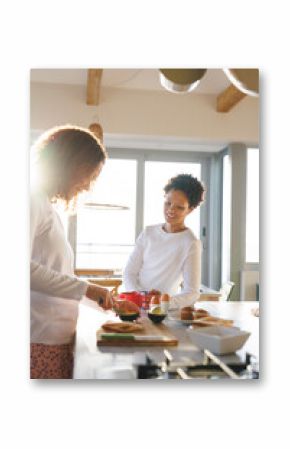 Happy diverse lesbian couple preparing breakfast in kitchen