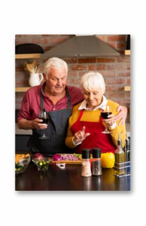 Happy caucasian senior couple preparing vegetables, drinking wine, embracing in kitchen, copy space